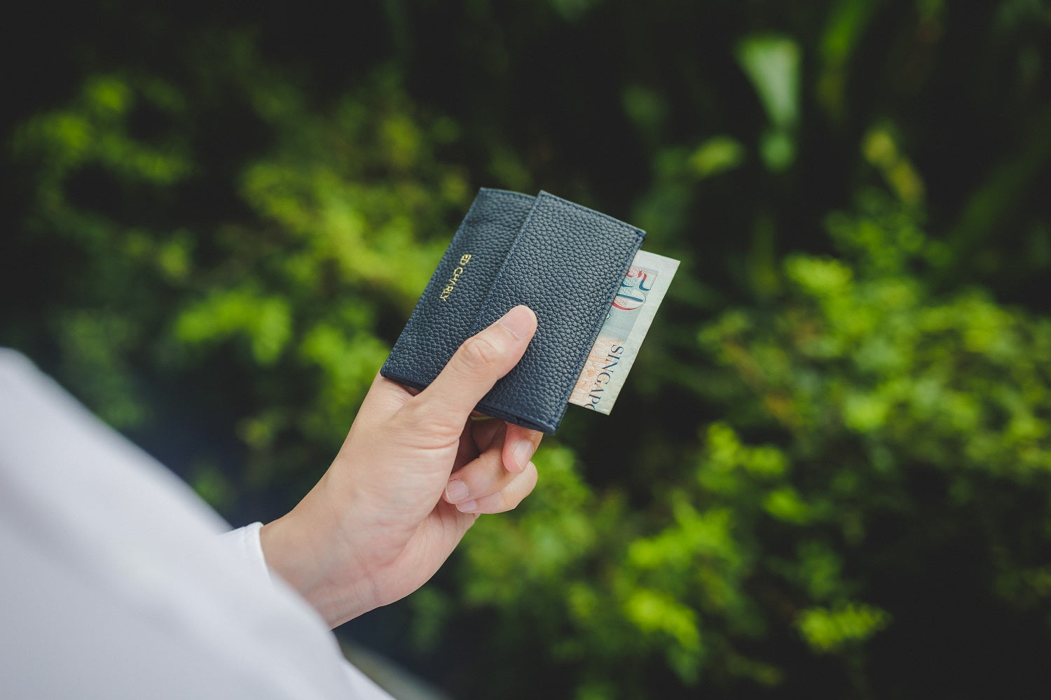 cash slot in the navy blue pebble grain Ed Classic wallet holding folded Singapore notes.