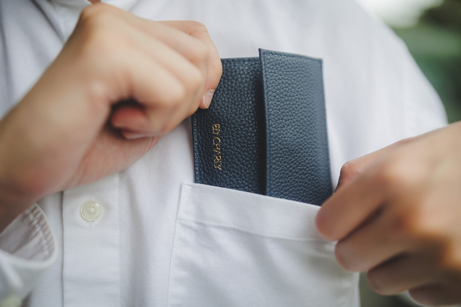 Navy blue pebble grain Ed Classic wallet put into front pocket.