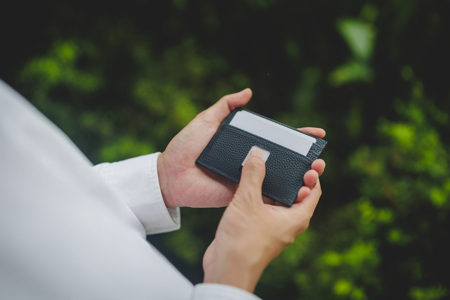 card sliding from the outer quick-access slot of the navy blue pebble grain Ed Classic wallet.